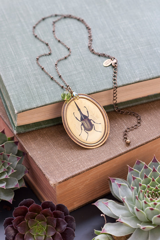 Beetle cameo pendant necklace on stack of vintage books