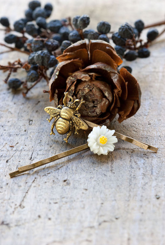 Daisy and bee gold hair pins next to dried flowers
